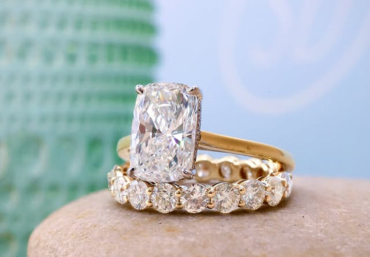 Gold ring with a large diamond and a smaller diamond-studded band on a stone surface.