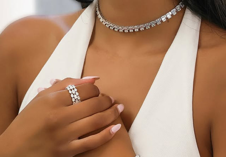 Close-up of a person wearing a silver necklace, ring, and bracelet on a white background