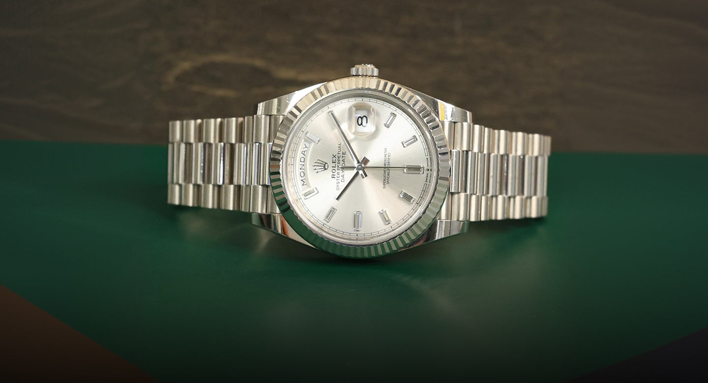 Silver watch with a detailed face on a green and brown gradient background