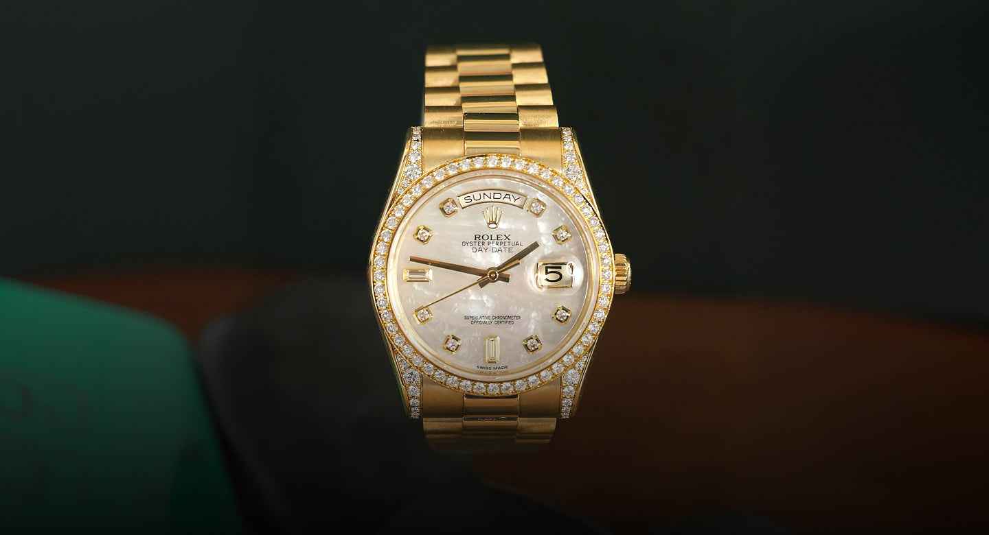 Gold wristwatch with diamond-studded bezel on a dark background