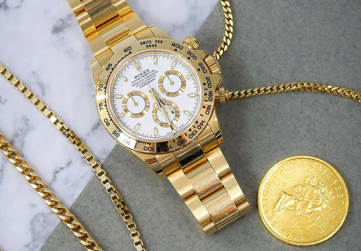 Gold watch and coin on a marble surface